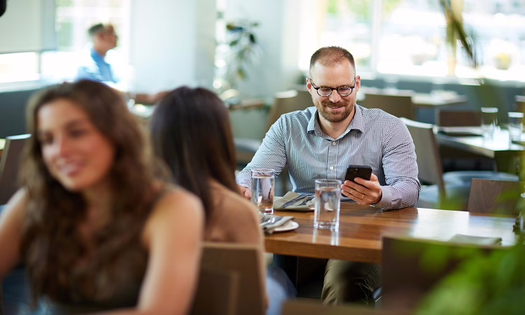 Man looking at his phone in a restaurant.