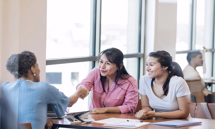 Mature woman shakes hands with loan officer. She and her college age daughter are meeting with the loan officer about obtaining a student loan.