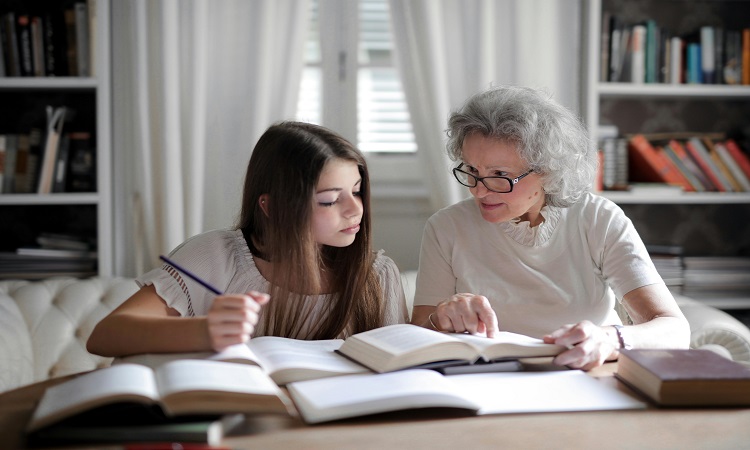 Grandmother teaching young granddaughter about money at home.