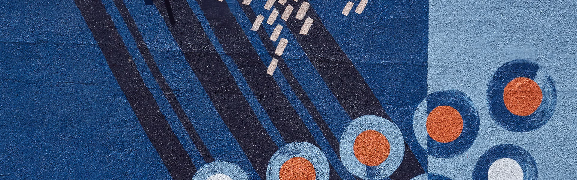 Blue and orange design on brick wall for Upcoming Merger page.